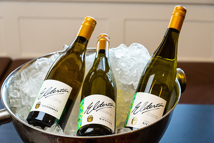 Three Elderton wine bottles—one Chardonnay and two Riesling—chilled in a large bowl of ice